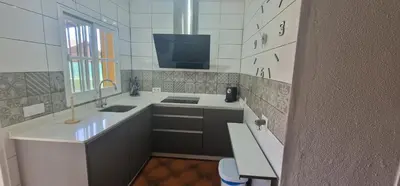 a white kitchen with a sink and a tv at Chalet a 2 kilometros de la playa in Chiclana de la Frontera