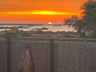 a sunset over a body of water with a fence at Chalet a 2 kilometros de la playa in Chiclana de la Frontera