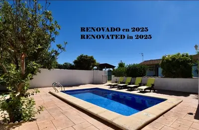 a swimming pool in a yard with chairs next to a wall at Chalet La Alberca in Chiclana de la Frontera