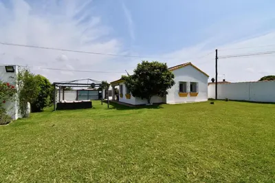 a yard with a white house and a green lawn at Chalet La Alberca in Chiclana de la Frontera