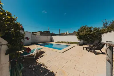 a patio with a swimming pool and two lawn chairs at Chalet La Alberca in Chiclana de la Frontera