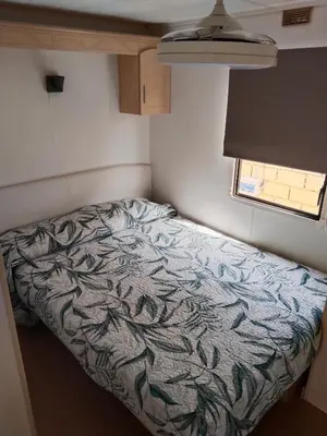 a small bedroom with a bed in a trailer at OHANA in Chiclana de la Frontera