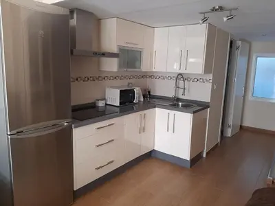 a kitchen with white cabinets and a sink and a microwave at Loft Las piletas in Sanlúcar de Barrameda