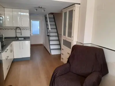 a room with a chair in a kitchen with a staircase at Loft Las piletas in Sanlúcar de Barrameda