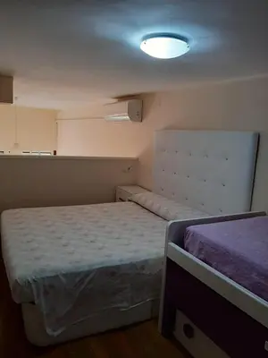 a small bedroom with two beds and a light at Loft Las piletas in Sanlúcar de Barrameda