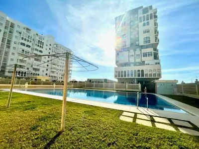 a swimming pool in front of two tall buildings at GATU Villa Salada, junto la playa, parking, terraza, aire acc, piscina, wifi Sólo familias o grupos mayores de 21 años in El Puerto de Santa María