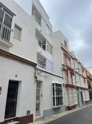 a white building with barred windows on a street at Piso en el centro in San Fernando