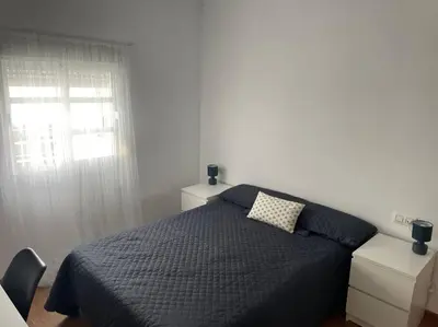 a bedroom with a bed with a blue comforter and a window at Piso en el centro in San Fernando