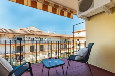 a balcony with chairs and a table with wine glasses on it at Las Olas Chipiona in Chipiona