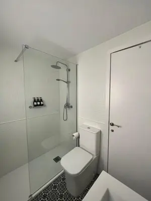 a white bathroom with a shower and a toilet at Las Olas Chipiona in Chipiona