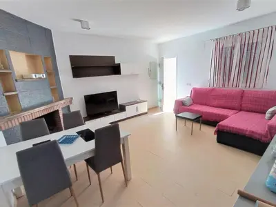 a living room with a pink couch and a table at Villa Bonita in Conil de la Frontera