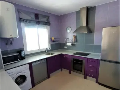 a kitchen with purple cabinets and a window and a dishwasher at Villa Bonita in Conil de la Frontera