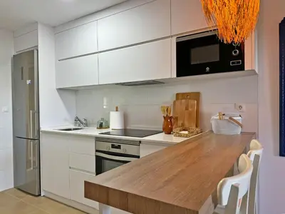 a kitchen with white cabinets and a wooden counter top at Apartamento Dunas Candor - Ole Solutions in Rota
