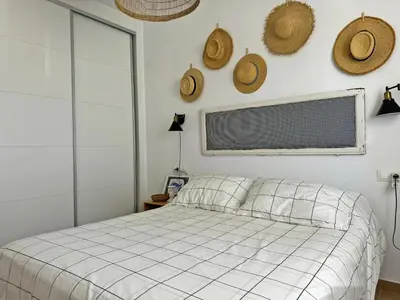 a bedroom with a bed and straw hats on the wall at Apartamento Dunas Candor - Ole Solutions in Rota