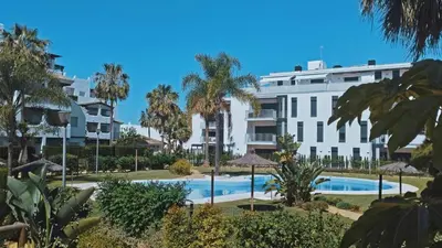 a large white building with a swimming pool and palm trees at Apartamento Dunas Candor - Ole Solutions in Rota