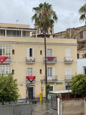 a building with a palm tree in front of it at Casa de Santa María in El Puerto de Santa María
