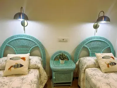 two twin beds in a room with blue chairs at Casa de Santa María in El Puerto de Santa María
