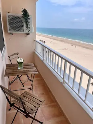 a balcony with a table and chairs and the beach at GATU PREMIUM Villa Turquesa Playa y Parking in Cádiz