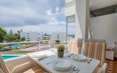 a white table with plates and wine glasses on a balcony at Azvalia - Valdelagrana Puerto Príncipe, Playa, piscina, parking in El Puerto de Santa María