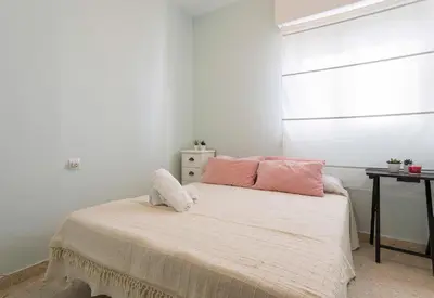 a bedroom with a bed with two pink pillows at Azvalia - Valdelagrana Puerto Príncipe, Playa, piscina, parking in El Puerto de Santa María