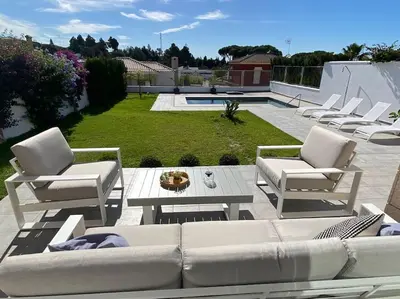 a patio with a couch and chairs and a table at Exclusiva Villa Lujo con piscina privada by Chiclana Dreams in Chiclana de la Frontera