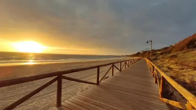 a wooden boardwalk leading to the beach at sunset at Villa Mar de Las Redes in El Puerto de Santa María