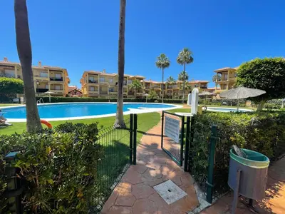 a gate leading to a swimming pool with palm trees at Margaritas 27 in Chiclana de la Frontera