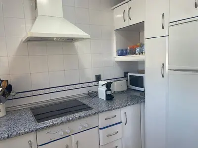 a kitchen with white cabinets and a white refrigerator at Margaritas 27 in Chiclana de la Frontera