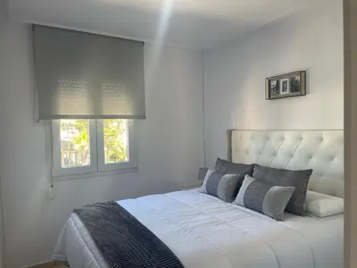 a white bedroom with a bed and two windows at Margaritas 27 in Chiclana de la Frontera