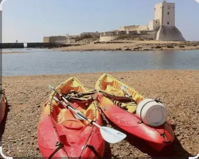 a kayak on a beach with a lighthouse in the background at Casa Pelicano in Chiclana de la Frontera