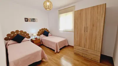 a bedroom with two beds and a large cabinet at Villa Candari in Chiclana de la Frontera