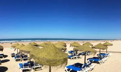 a beach with chairs and umbrellas and the ocean at Villa Candari in Chiclana de la Frontera
