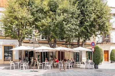a group of people sitting at tables with umbrellas at Casa Dionisio - Súper central y tranquilo con terraza y parking in Jerez de la Frontera