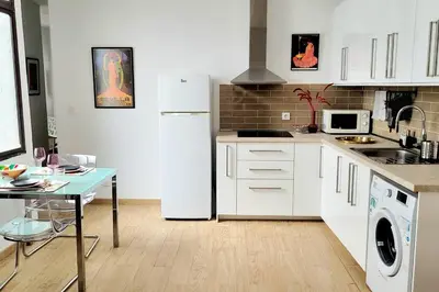 a kitchen with a white refrigerator and a table at Casa Dionisio - Súper central y tranquilo con terraza y parking in Jerez de la Frontera