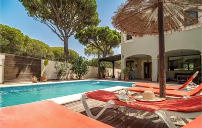 a swimming pool with chairs and an umbrella at Gorgeous Home In Conil De La Frontera in Conil de la Frontera