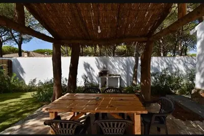 a wooden table and chairs under a wooden pergola at Casa Palmito in Chiclana de la Frontera