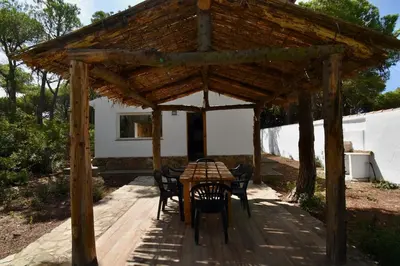 a wooden table and chairs under a wooden pergola at Casa Palmito 2 in Chiclana de la Frontera