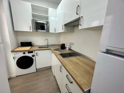 a small kitchen with white cabinets and a dishwasher at Apartamento Nebro Sol, En el Corazón de Cádiz in Cádiz