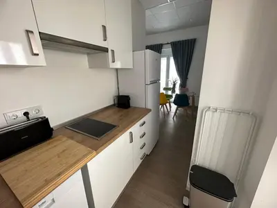 a kitchen with white cabinets and a wooden counter top at Apartamento Nebro Sol, En el Corazón de Cádiz in Cádiz