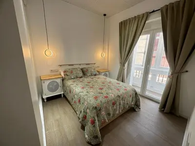 a bedroom with a bed and a tv and a window at Apartamento Nebro Sol, En el Corazón de Cádiz in Cádiz