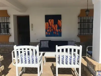 two white chairs and a table on a patio at El Magnolio in Chiclana de la Frontera