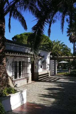 a white building with a gate and palm trees at Sunny Home pool & Garden in Arcos de la Frontera in Arcos de la Frontera