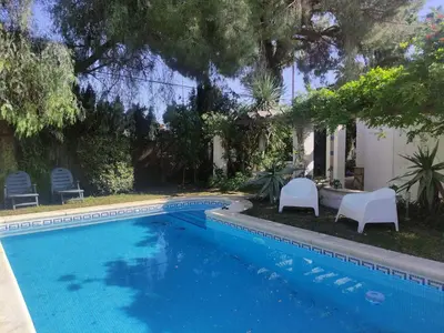 a swimming pool with two white chairs next to a house at Sunny Home pool & Garden in Arcos de la Frontera in Arcos de la Frontera