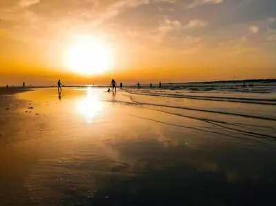 a group of people walking on the beach at sunset at Apartamento Irina Sol in Sanlúcar de Barrameda