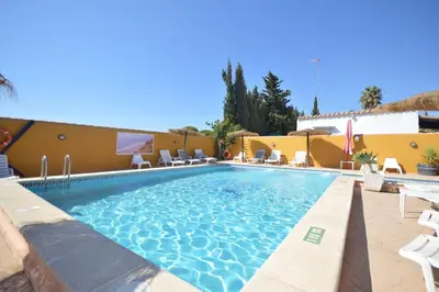 a swimming pool with chairs and a building at Boho Glamping en Complejo Rural el Mayorazgo in Cádiz