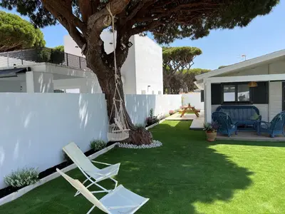 a yard with two lawn chairs and a tree at La casita del sopapo in Chiclana de la Frontera