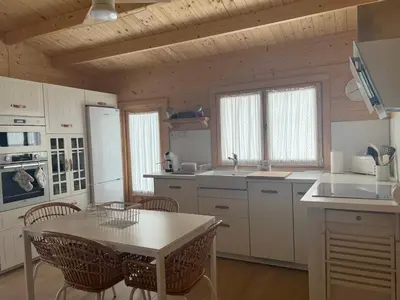 a kitchen with white cabinets and a table and chairs at La casita del sopapo in Chiclana de la Frontera