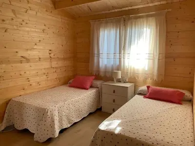 two beds in a wooden room with a window at La casita del sopapo in Chiclana de la Frontera