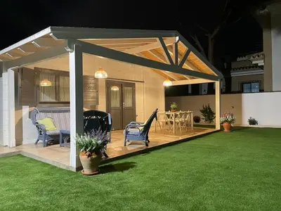 a pavilion with chairs and a table on a lawn at La casita del sopapo in Chiclana de la Frontera
