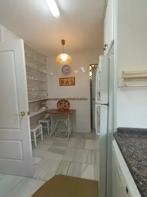 a kitchen with a table and a refrigerator at Casa playa El Ancla Puerto Santa María in El Puerto de Santa María